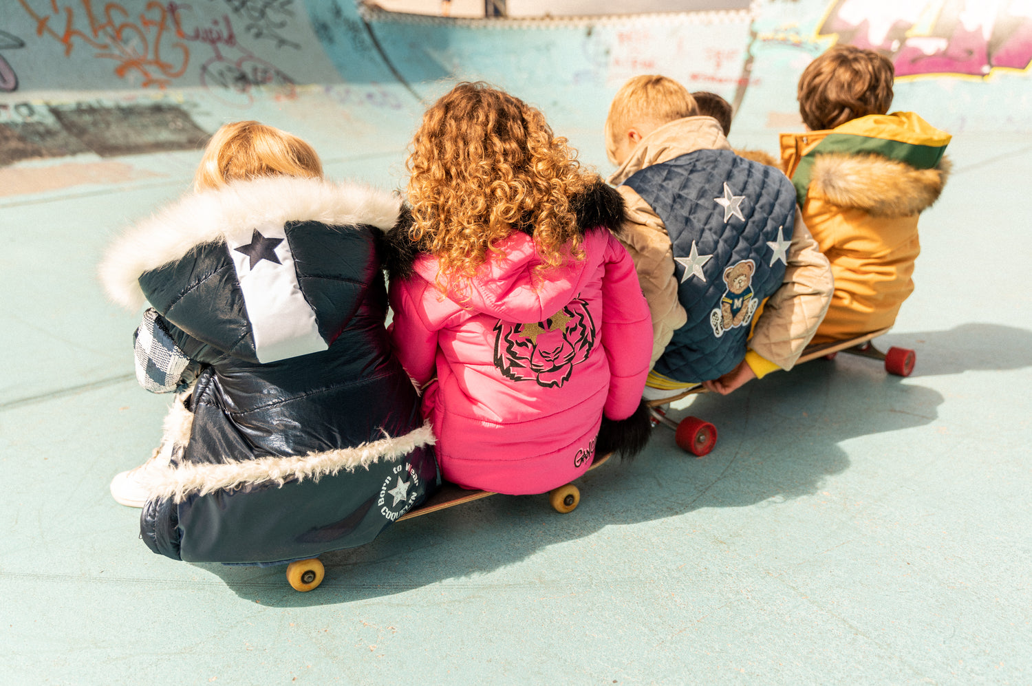 Niños con abrigo sentados en tablas de skate