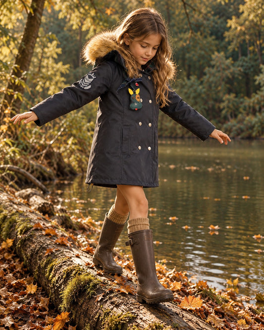 Niña con abrigo Belgravia azul marino junto a un lago otoñal