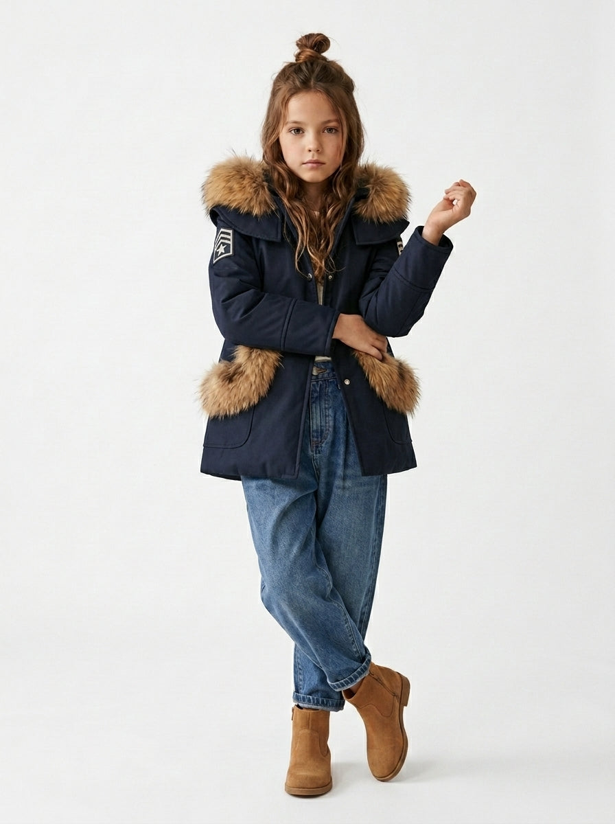 Niña con abrigo Cotswolds de lana azul marino, vaqueros y botas marrones